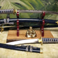 sword and dagger display stand with a live-edge oak base and red-brown wooden holders displaying blue and gold swords
