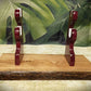 sword and dagger display stand with a natural live-edge oak base and glossy burgundy-purple wooden holders