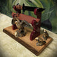 sword and dagger display stand with a live-edge brown wood base, glossy purple-red supports and black blade